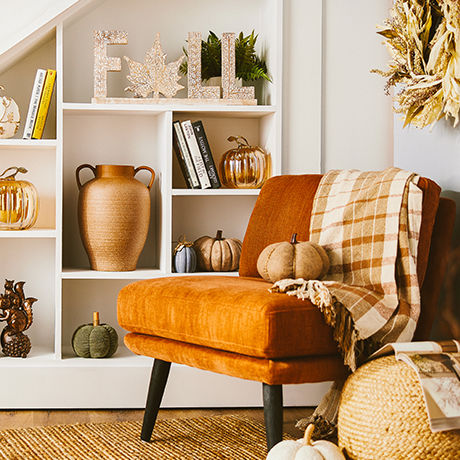 Post-modern velvet chair in-front of a bookcase filled with decor and books.