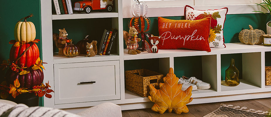 A variety of different fall decor arranged on a bookcase.