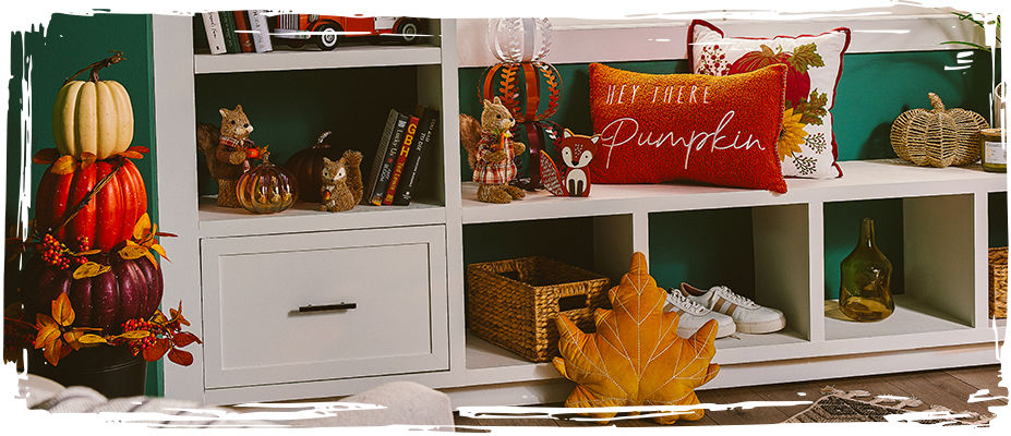 A variety of different fall decor arranged on a bookcase.