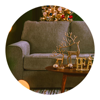 A gray sofa with a lite Christmas tree in the background.